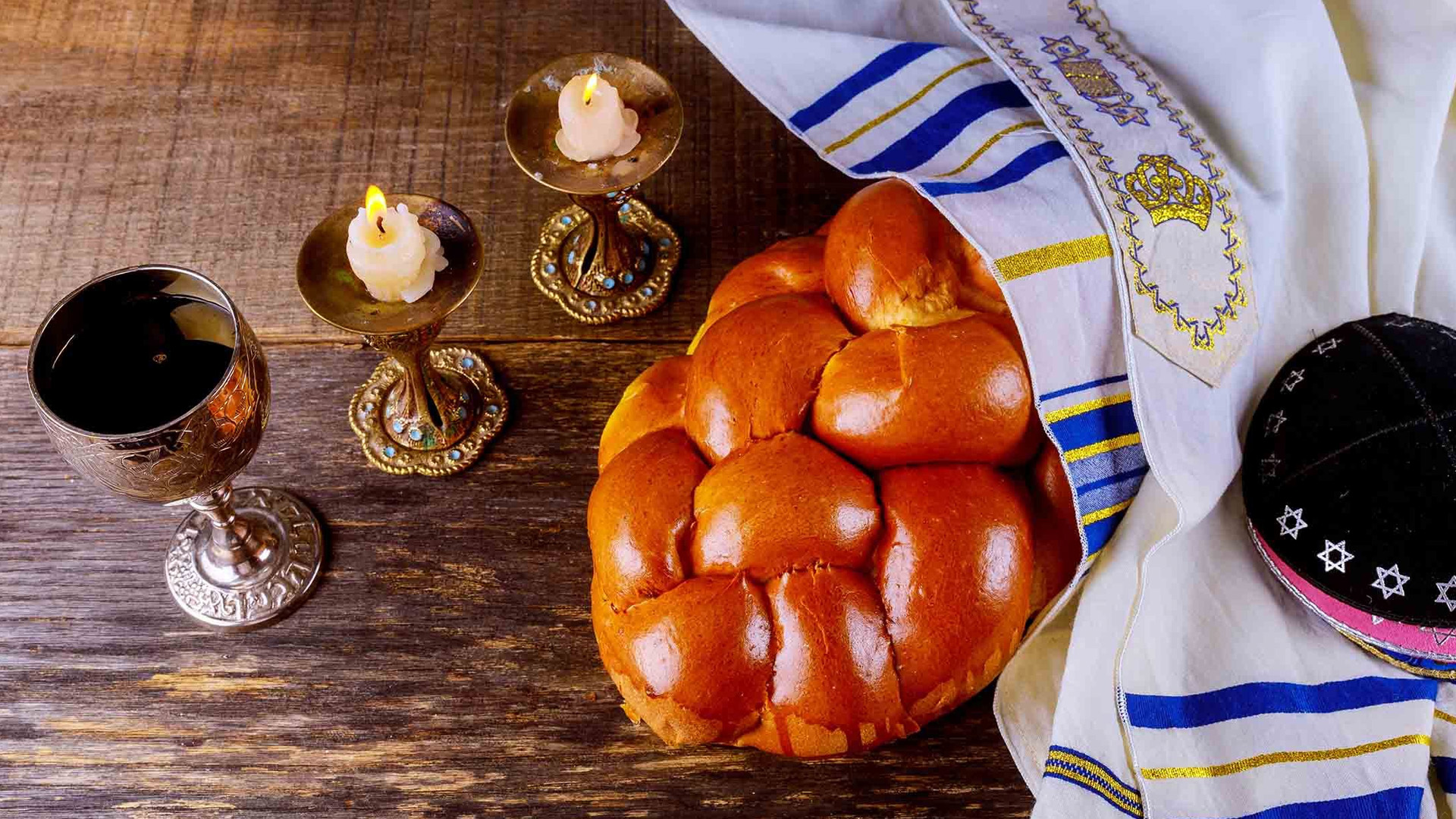 Image of challah, Kiddush cup and candles for Shabbat.