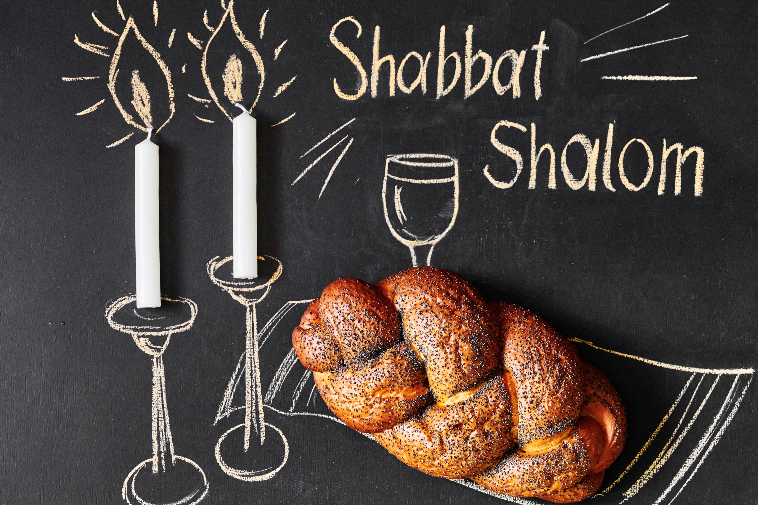Image of two Shabbat candles and a single loaf of challah