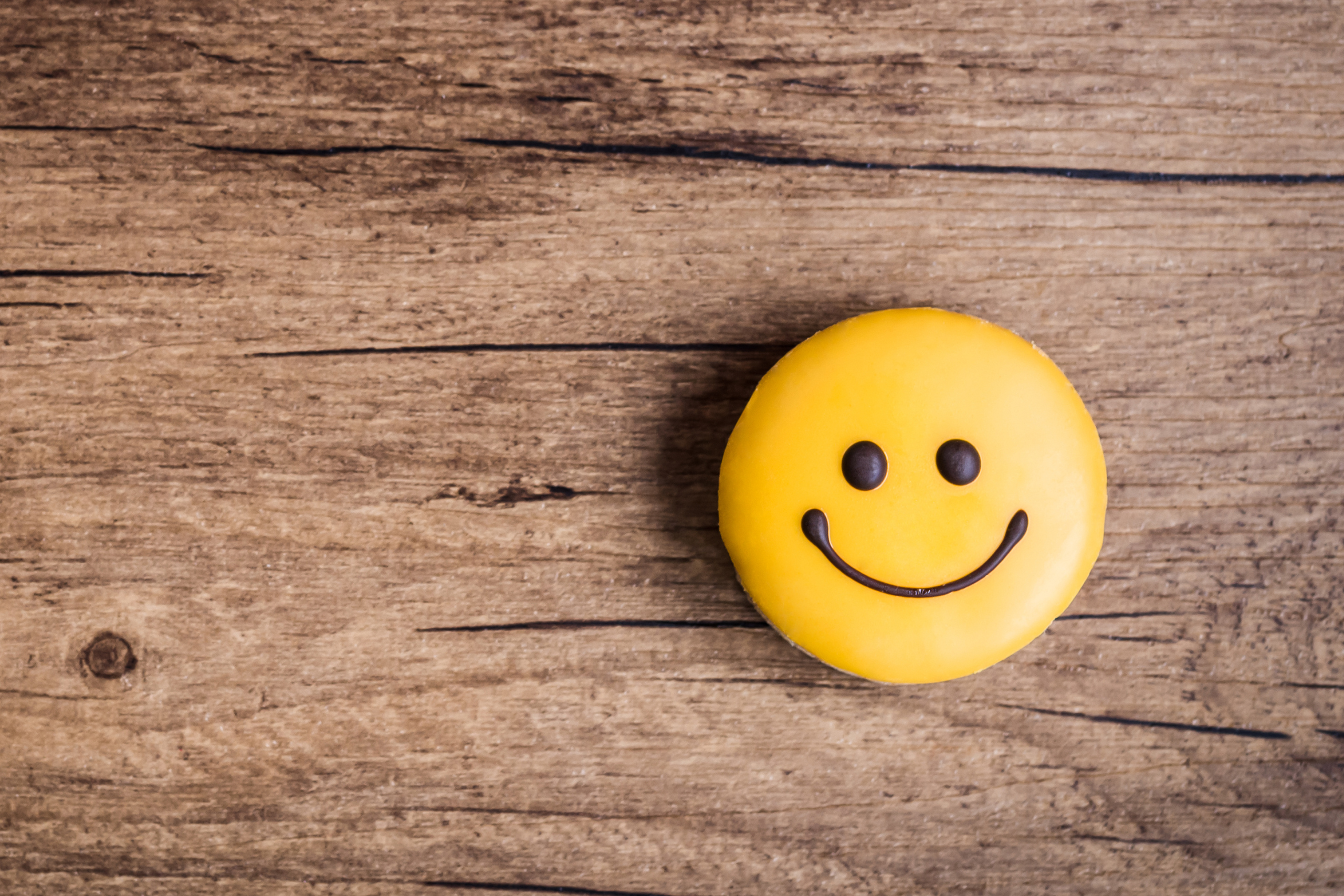 Image of a smiley face button on a wooden table